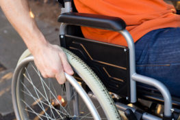 persona en silla de ruedas con su mano sobre la rueda