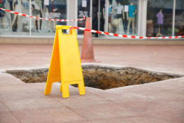 yellow warning sigh at broken sidewalk