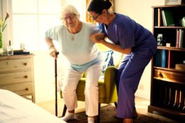 Lady helps elder up from chair