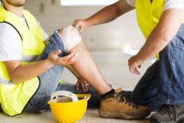 construction worker with broken leg being assisted by co-worker