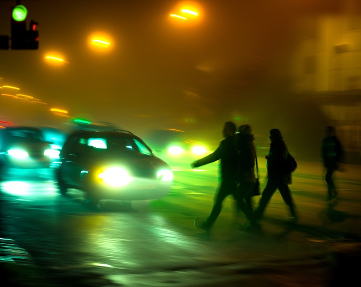 Pedestrians about to be hit by a car in the dark
