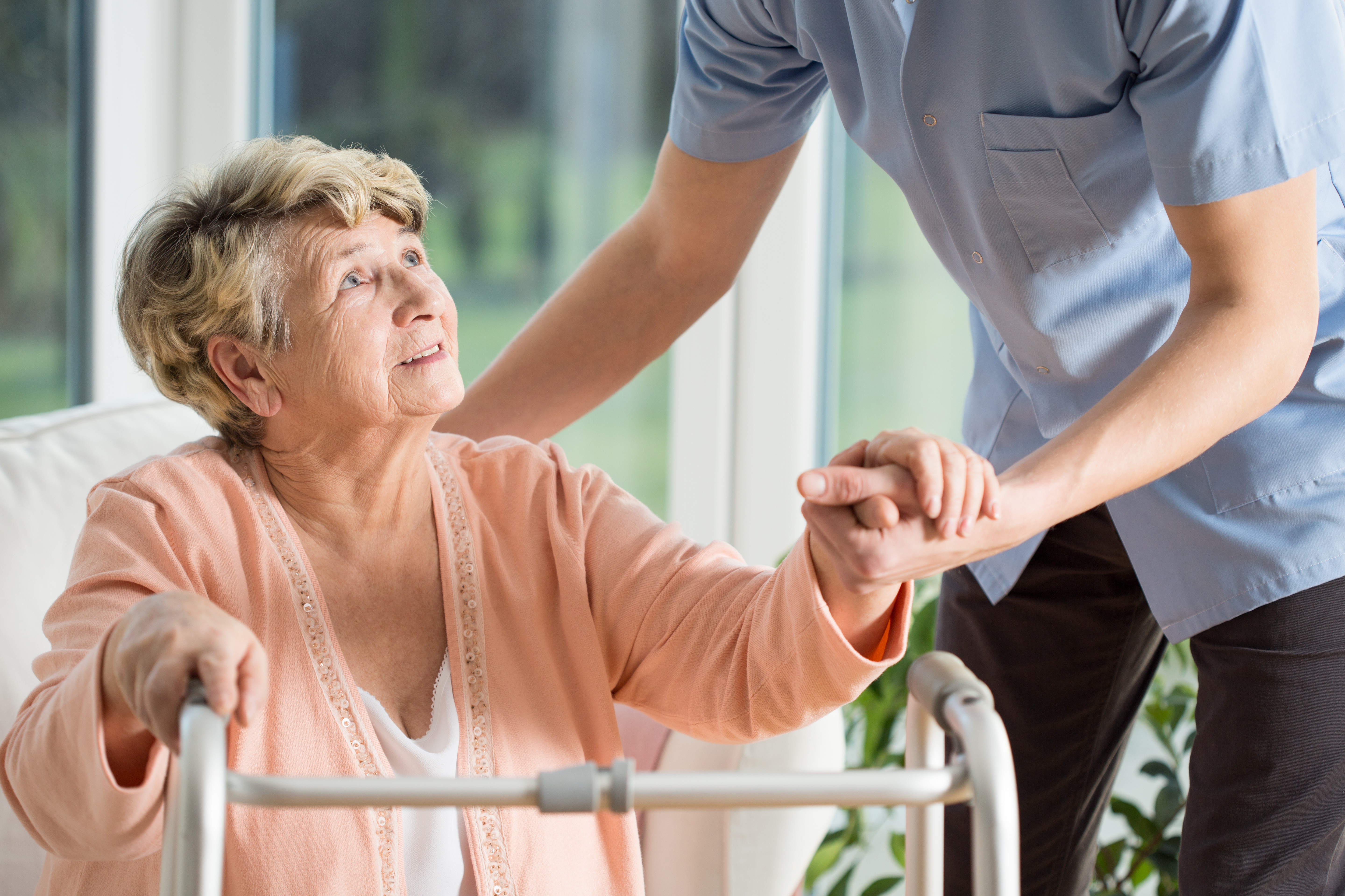 nursing home worker helping woman with walker