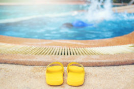 pair of yellow flip flops poolside with drowning child in water