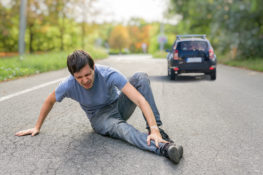 Hit and run concept. Injured man on road in front of a car