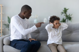 Angry single black father scolding stubborn fussy little african son closing ears not listening ignoring dad punish small mixed race kid boy for bad behavior, parent and child family conflict concept F