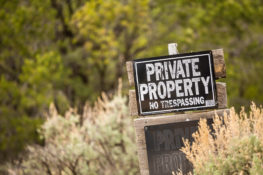 private property sign on wood pole in brush