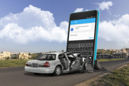 graphic of gray car wrecked front end by oversized smartphone in road