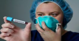 a woman holding a lab specimen indicating coronavirus positive