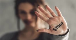 woman with the word "stop" written on her hand trying to stop abuse