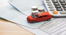 toy car beside money and papers representing car insurance