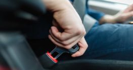 Driver putting on seat belt as a car safety feature.
